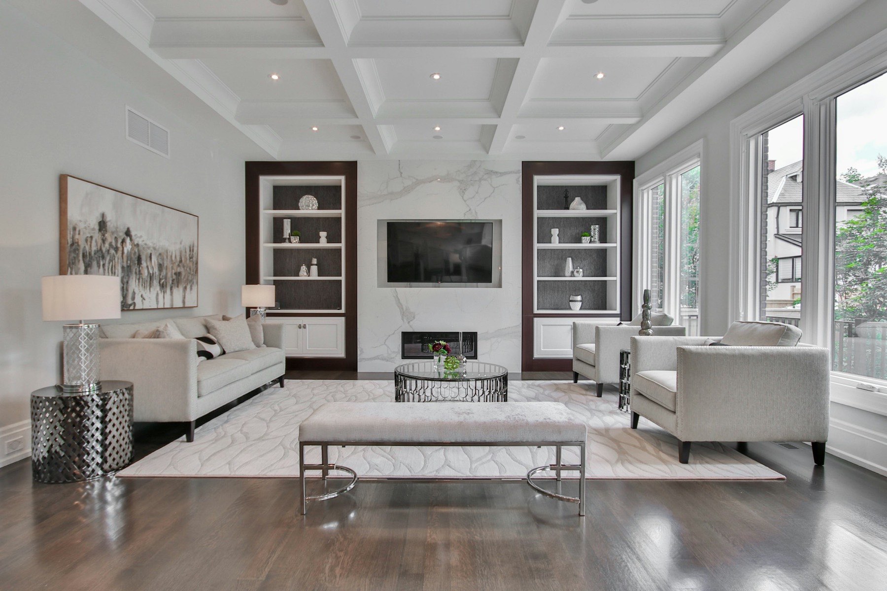 Living room with a coffered ceiling, marble fireplace surround, built-in shelving, and dark hardwood floors.