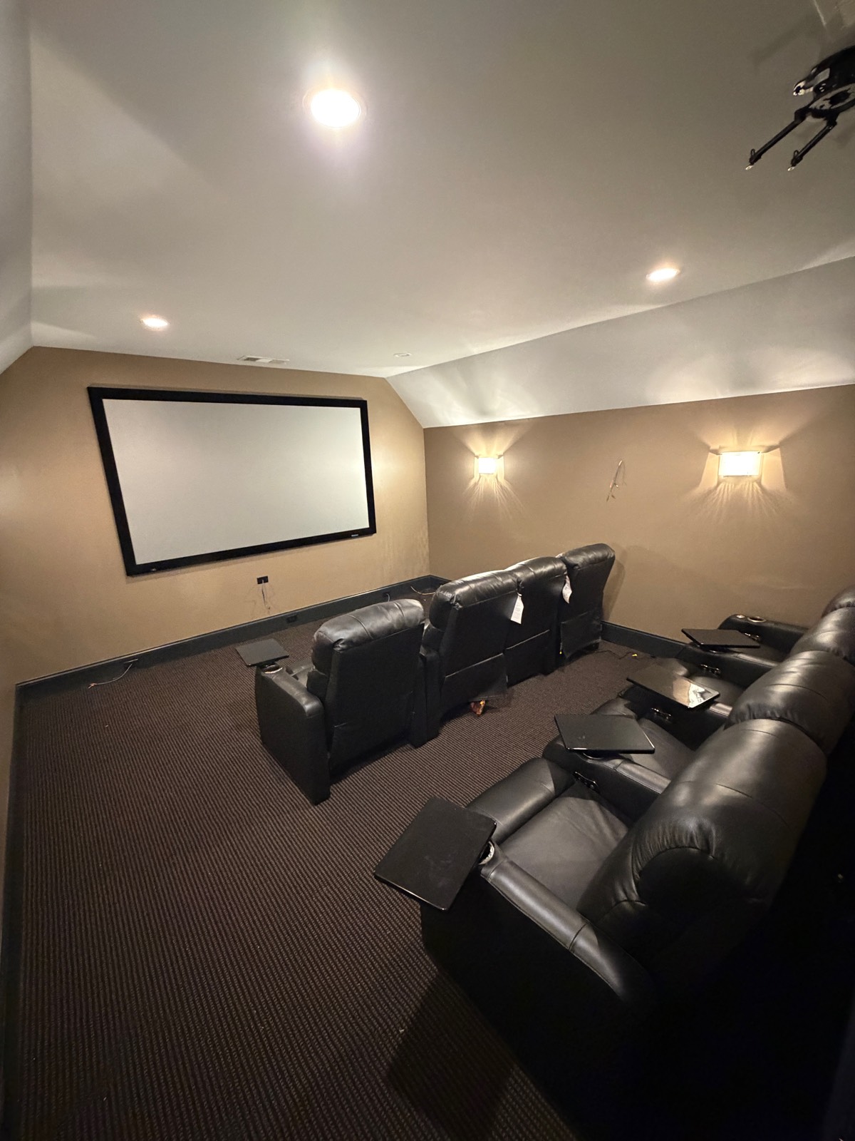 Finished home theater in a converted bonus room: projection screen, tiered seating riser, and leather recliners.